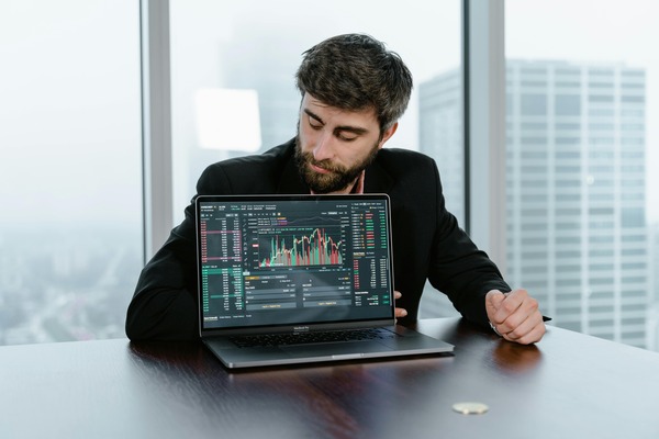 Man with a laptop showing trading charts