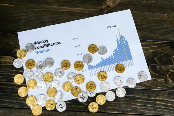 Crypto coins next to a weekly volume chart