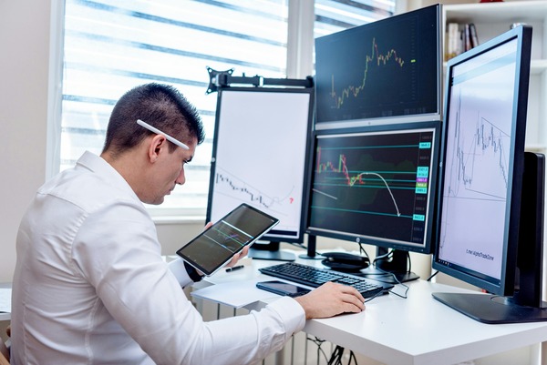 Trader at a desk with multiple chart screens