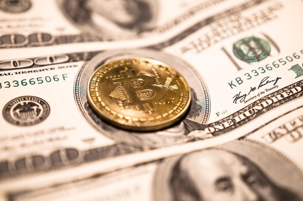 Bitcoin coin on hundred dollar bills