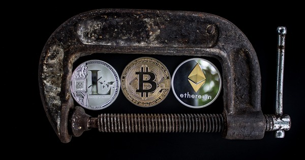 Litecoin, bitcoin and ethereum coins in a clamp