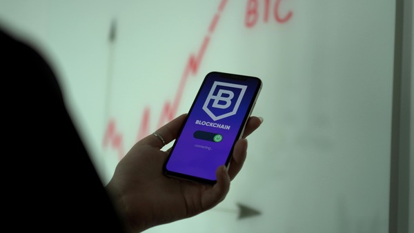 Hand holding a phone with a blockchain app