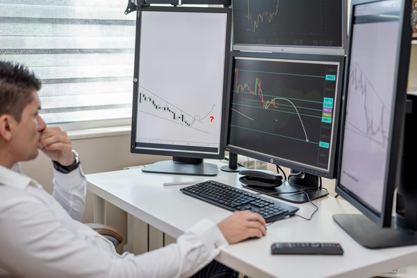 Trader watching charts on several monitors