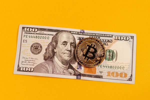 Bitcoin coin on a dollar bill against yellow