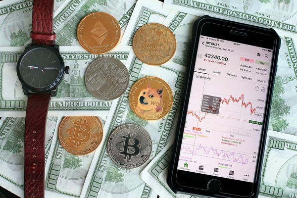 Phone with a chart next to coins and a watch