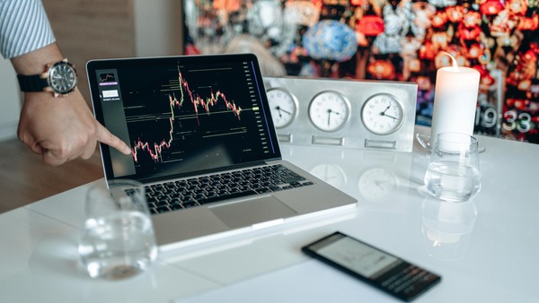 Hand pointing at a chart on a laptop screen
